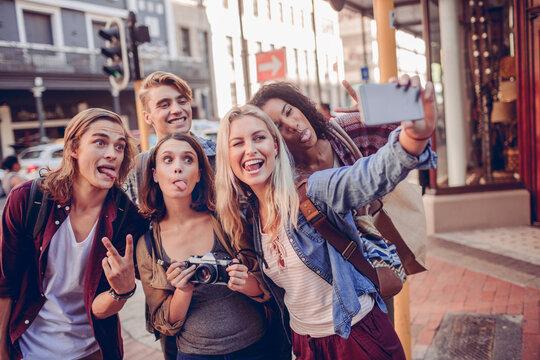Young adult friends taking playful selfie on city street