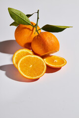 two whole oranges and slices with leaves on a white background