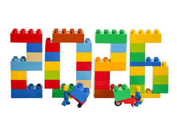 Obraz premium The numbers 2026 made from different colored Lego bricks and workers on a white background.