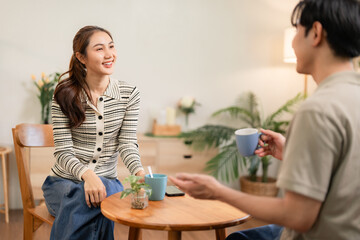 Asian adult couple sharing happy moments enjoying relaxed conversation at cozy home living room setting for romantic intimate connection