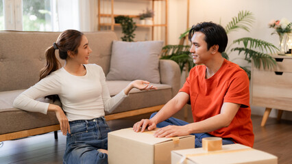 Asian couple discuss new home move logistics packing unpacking boxes apartment Happy young adults plan future together relocating property