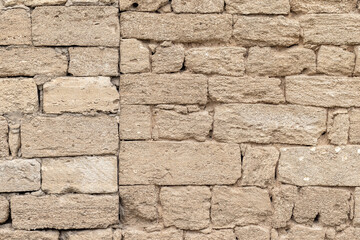 Fototapeta premium A textured shell rockwall made of irregular, weathered blocks in neutral beige tone