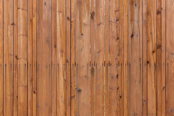 A close-up front view of a wooden fence made from vertical brown planks
