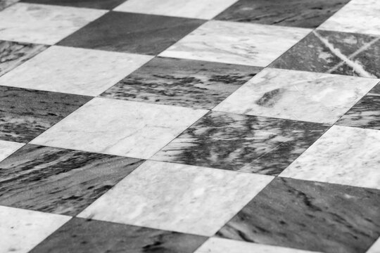 A close-up view of a black and white checkered marble floor - Powered by Adobe