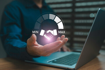 Businessman holding a digital handshake icon with performance meter concept on laptop background, symbolizing partnership, trust, collaboration, and successful business negotiation.