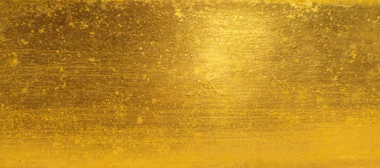 Gold wall texture background. Yellow shiny gold foil paint on wall sheet with gloss light reflection, vibrant golden paper luxury wallpaper