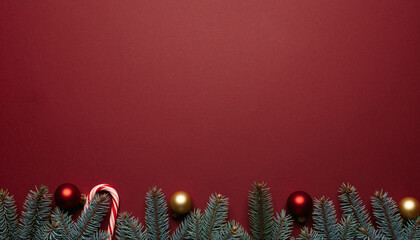 Christmas fir branches with red gold baubles and candy canes on red background