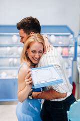 Man presenting a jewelry gift box to a surprised woman in a modern jewelry store, capturing a beautiful moment filled with love, excitement, and happiness in their relationship