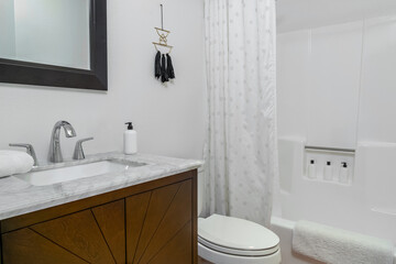 White modern bathroom interior. Marble sink, wood cabinet, and shower
