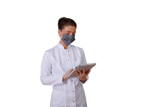 Doctor woman in lab coat wearing a protective face mask using a digital tablet for healthcare data