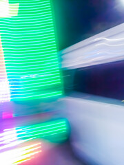 Colorful, fluorescent swirls of light create a dynamic and energetic abstract composition. Blurred streaks of purple, blue, and gold give the impression of rapid, surreal movement.