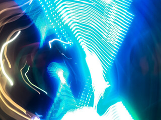 Colorful, fluorescent swirls of light create a dynamic and energetic abstract composition. Blurred streaks of purple, blue, and gold give the impression of rapid, surreal movement.