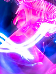 Colorful, fluorescent swirls of light create a dynamic and energetic abstract composition. Blurred streaks of purple, blue, and gold give the impression of rapid, surreal movement.