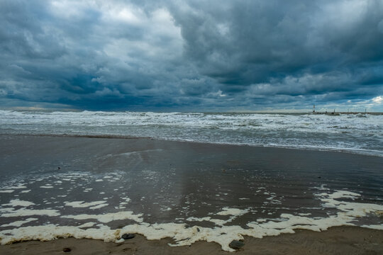 chaotic ocean view with storm clouds, fiery clouds hover above choppy waters and damp shoreline