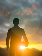 Engineer Silhouette Holding Helmet in Morning Light
