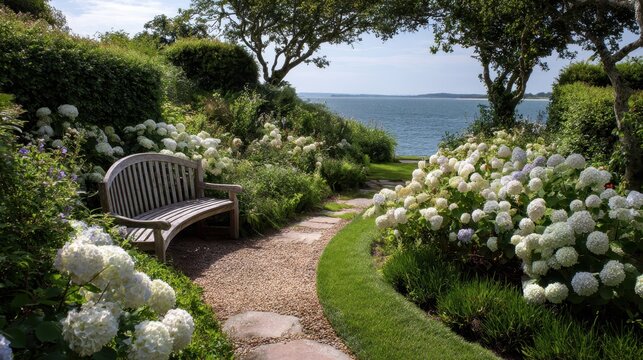 Coastal garden path winds past a weathered wooden bench amid white hydrangeas toward sparkling blue water and an open sky, a peaceful seaside retreat for relaxation