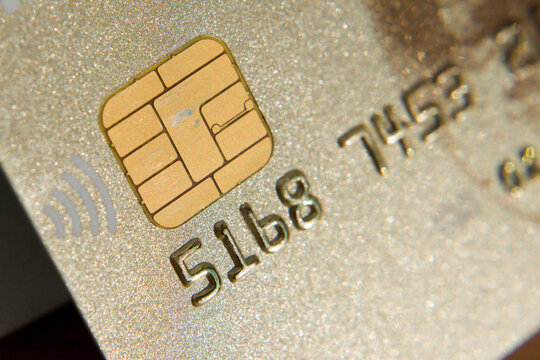 Close-up picture of a golden credit card. A microchip and numbers on a bank card.