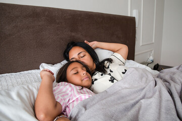A woman and a child are sleeping together on a bed