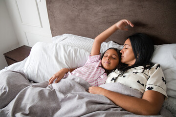 A woman and a child are sleeping in bed