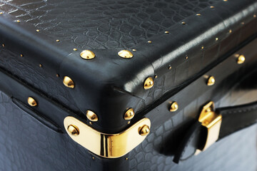 Black rare suitcase, leather case. Vintage suitcase-briefcase with a handle made of genuine black leather close-up. Metal trim on the corner of the suitcase and rivets.