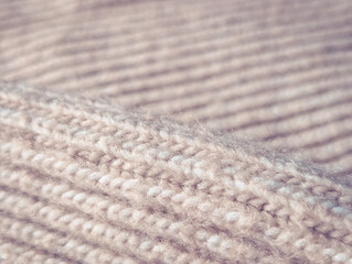 knitted texture macro background with fold and shallow focus in soft beige color