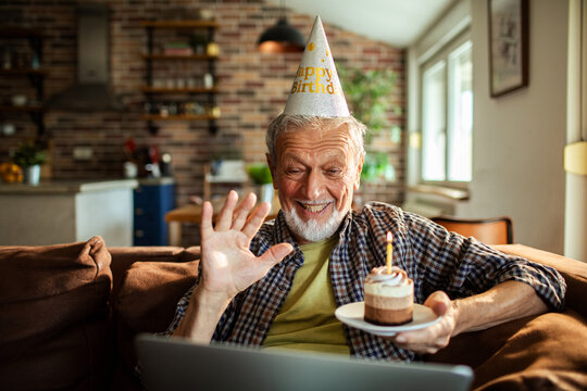 Happy senior man celebrating birthday on video call at home - Powered by Adobe