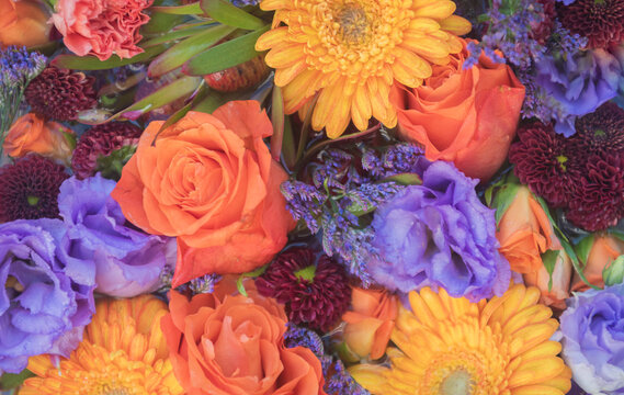arrangement or bouquet of various colorful flowers with purple lisianthus or Texas bluebell and yellow gerber and orange roses