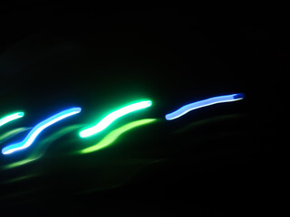 Elegant neon colored lines of light cut through the darkness of the night, giving a futuristic and dynamic impression of speed and movement, like a stunning digital abstract painting