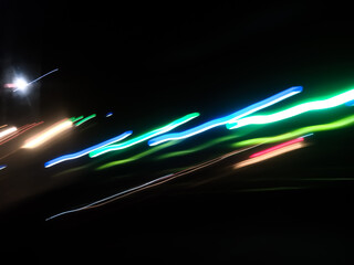 Elegant neon colored lines of light cut through the darkness of the night, giving a futuristic and dynamic impression of speed and movement, like a stunning digital abstract painting