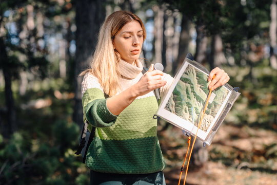 Woman hiking in forest navigating with map and compass
