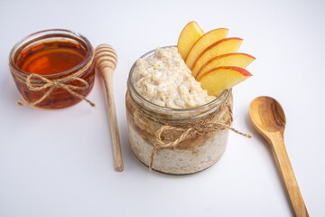 Oatmeal in a jar with apple, honey, and nuts isolated on white background