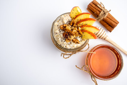 Oatmeal in a jar with apple, honey, and nuts isolated on white background