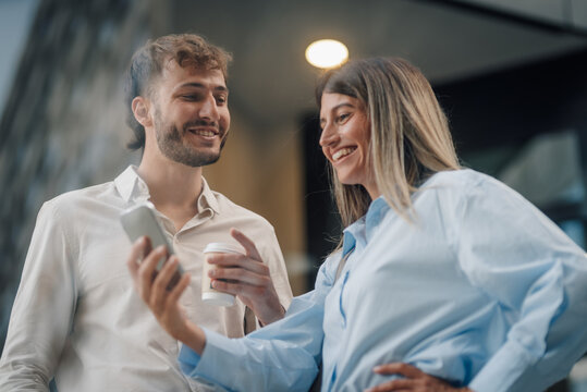 Business partners enjoying a coffee break and using a smartphone