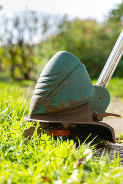 Gros plan sur un coupe bordure en train de faucher de l'herbe dans un jardin.