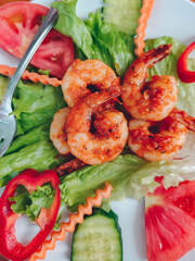 Delicious cooked shrimps in plate with salad, close-up.	