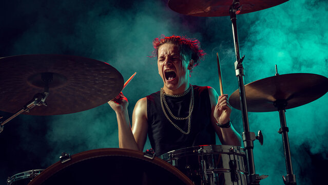 Rock drummer shouting with energy in green smoke and stage lighting. Concept of creative advertising, motivational visuals, emotional power, and self-expression in music culture. - Powered by Adobe