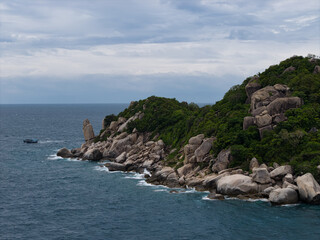 rugged shoreline facing turbulent ocean waters, severe rocky headlands merging with churning sea Koh Tao Thailand