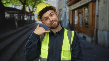 Man builder in hardhat and hi vis vest points finger to camera on street; friendly skilled...