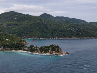 seaside fishing community, coastal harbor with boats and rocks, quiet bay featuring boats Koh Tao Thailand