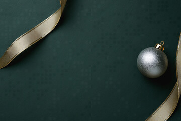 Elegant holiday card design featuring a deep forest green background and a delicate gold ribbon with a glittering silver ornament