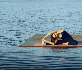 latin hispanic woman practicing yoga on the beach Revolved head-to-knee pose Female prace hatha yoga on summer coast, stretching in an asymmetrical seated asana Parivritta Janu Sirsasana Water surface