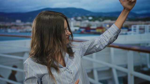 Woman mimes guitar strum with raised hand on cruise ship deck building; playfulness music vacation escape.