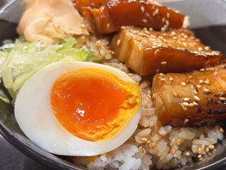 Half a boiled egg and grilled pork served on steamed rice .  steamed rice with boiled egg and grilled pork , so appetizing