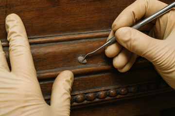 Restoration and Craftsmanship: Detailed close-up captures a craftsman meticulously restoring a vintage wooden furniture piece with great care.
