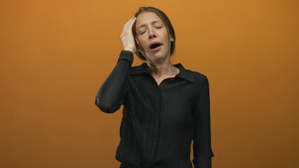 Young hispanic woman yawning with hand on head wearing black blouse and pearl earring in orange...