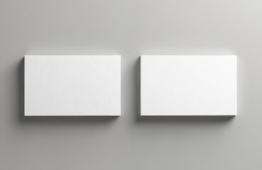 Two blank white business cards lie on grey surface. Clean mockup offers space for corporate identity design. Empty templates await branding. Minimalist object perfect for presentation, portfolio,