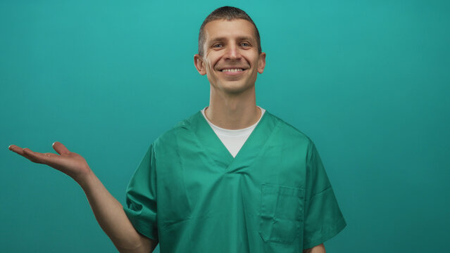 Caucasian male doctor in uniform with open hand smiling against green background isolated wall, presenting or introducing an idea.