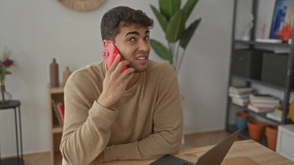 Fototapeta premium Man offers phone before calling home alongside young hispanic guy holding smartphone in indoor casual setting.
