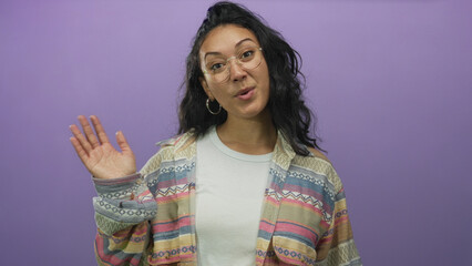 Fototapeta premium Woman showing raised hands and sticking tongue while wearing a patterned jacket in a purple studio; playful curiosity.