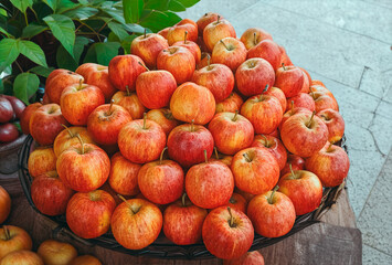 A vibrant close-up of fresh, ripe red and yellow apples abundantly displayed in a market setting in India, surrounded by green foliage.